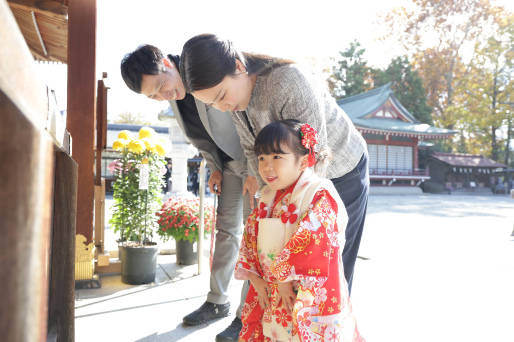 立川諏訪神社の本殿前で丁寧にお辞儀をする3歳のお嬢さんの七五三写真
