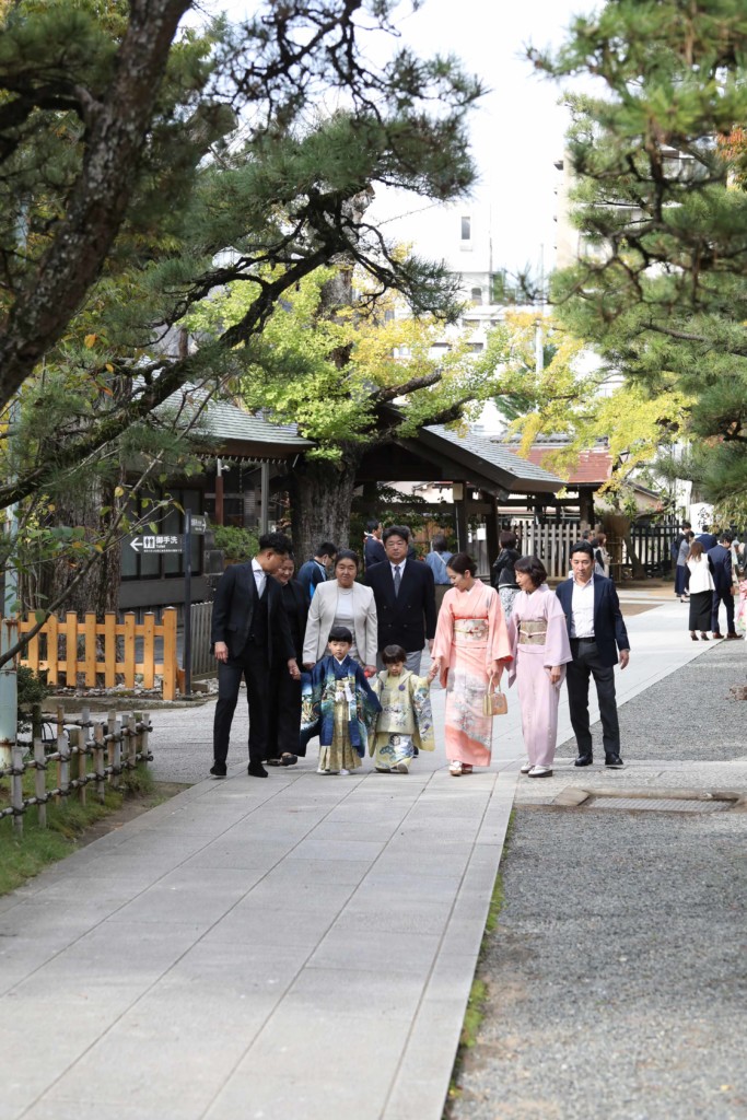 船橋大神宮の紅葉した参道を家族と親族9名で歩く七五三写真